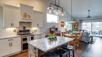 A modern kitchen with white cabinetry, a central island, stainless steel appliances, and pendant lighting.