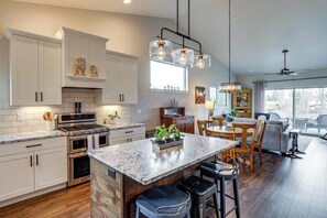 A modern kitchen with white cabinetry, a central island, stainless steel appliances, and pendant lighting. - Next to Public Golf Course! Kalispell Townhome (Kalispell)