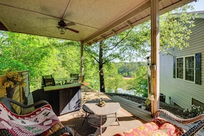Eine überdachte Veranda mit Tisch, Stühlen und einer gesteppten Couch.