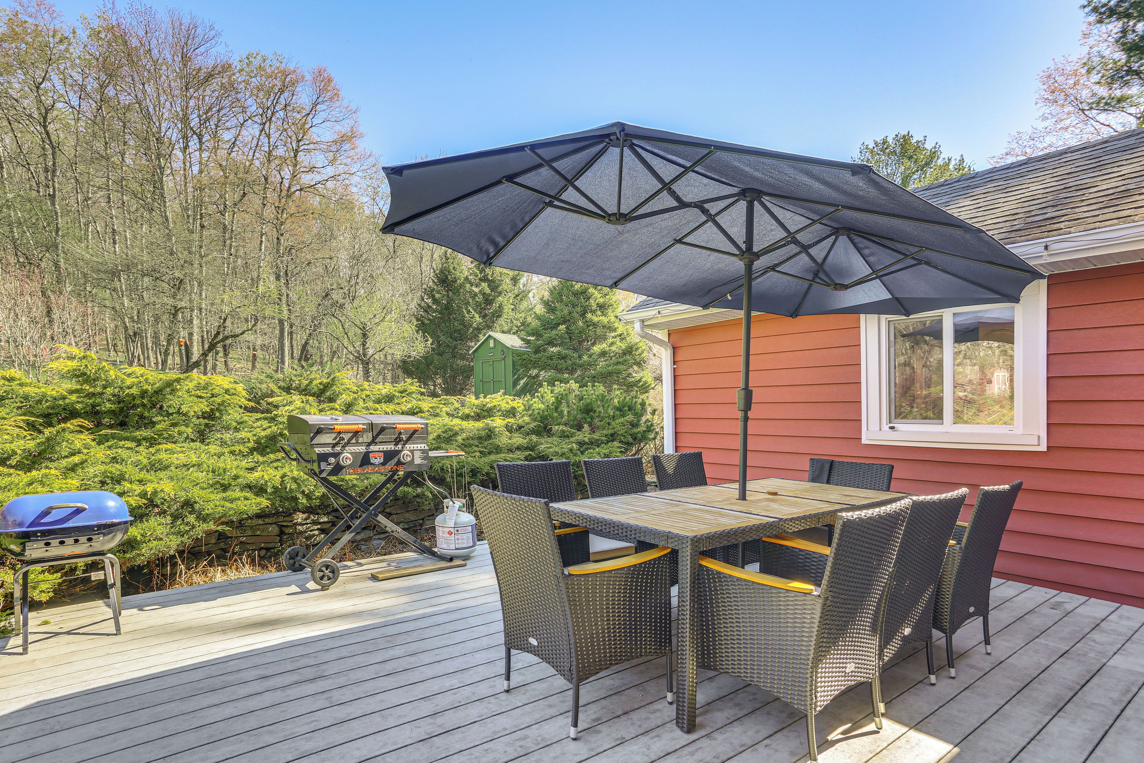 A deck with a table and chairs, a grill, and an umbrella.