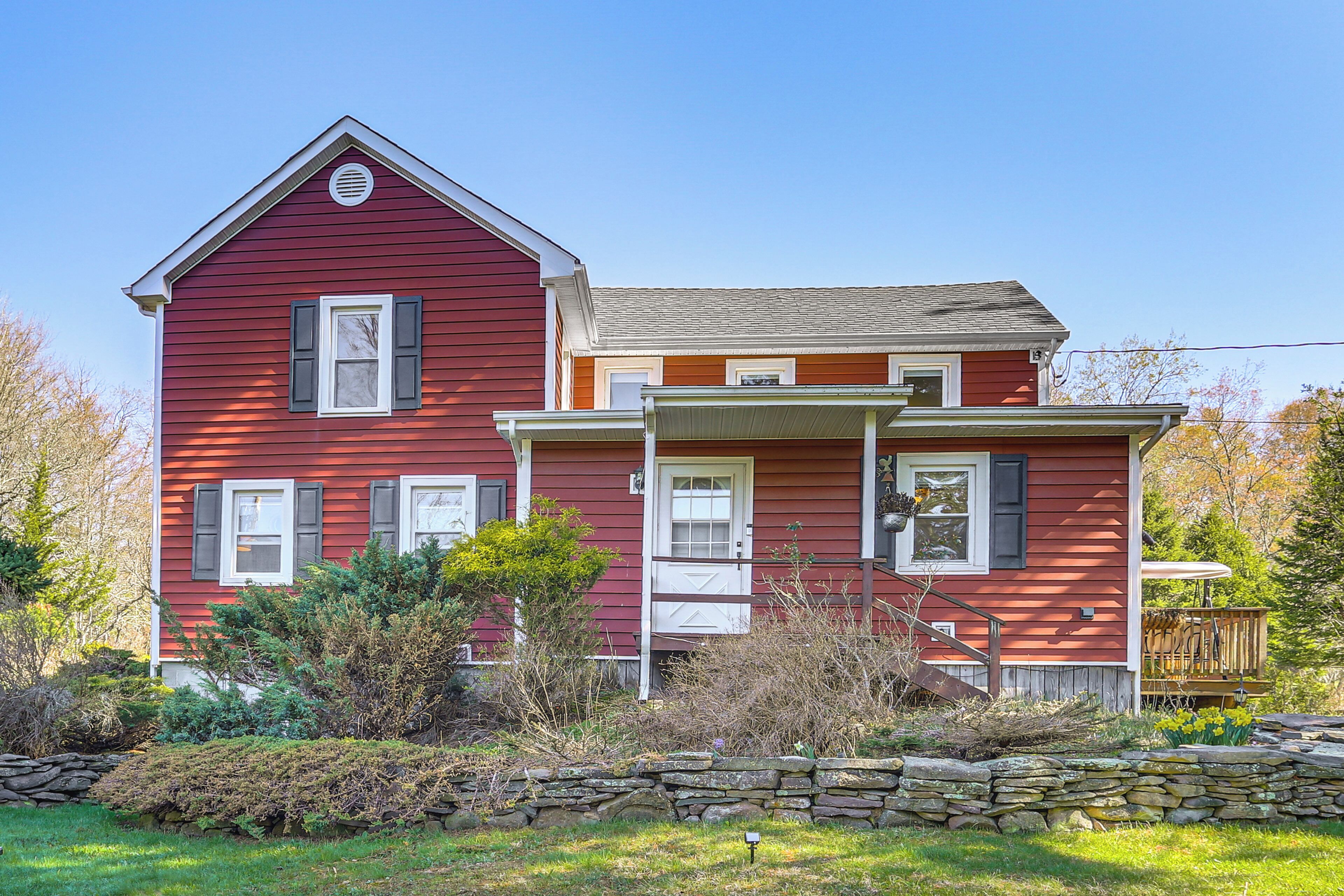 A two-story house with a stone wall in front, a porch, and a small deck.