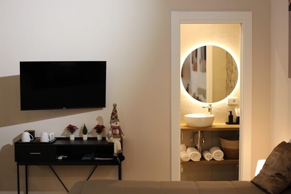 A modern hotel room with a flat-screen TV, a small console table with a coffee maker, and a cozy seating area. - WITHIN WALKING DISTANCE OF CENTRAL STATION AND NAPLES BUSINESS CENTER. (Napoli)