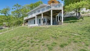 Ein zweistöckiges Haus mit Balkon, überdachter Veranda und Natursteinfassade.