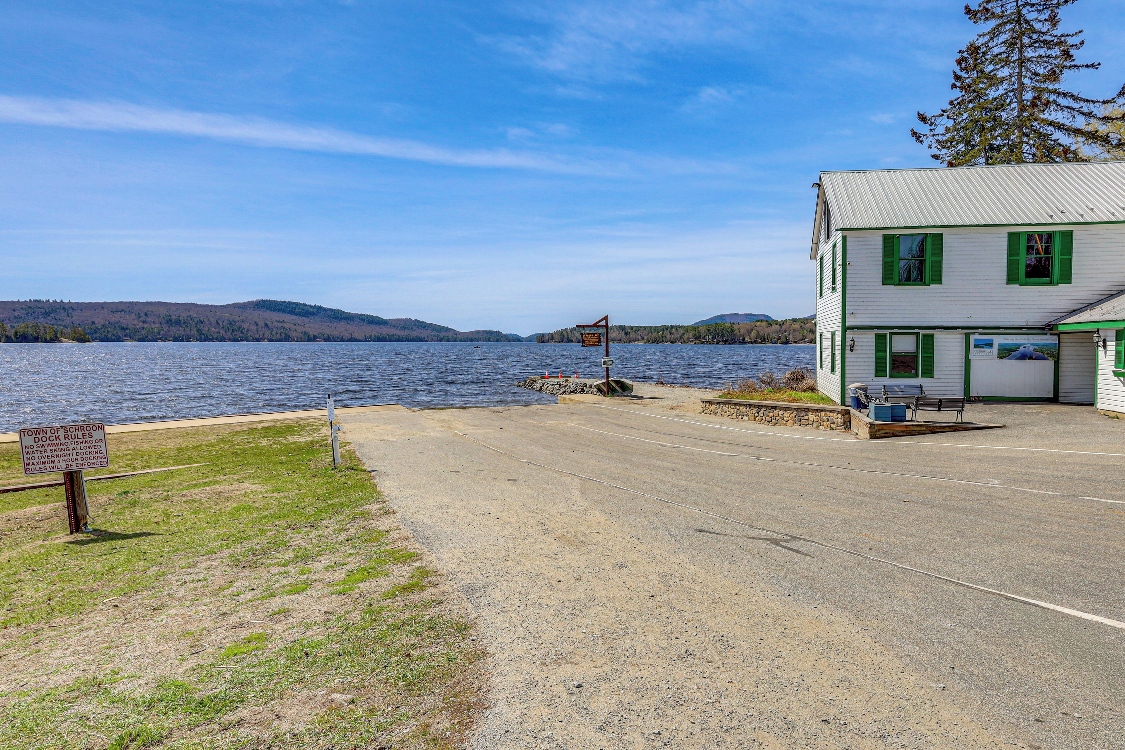 A dock with a sign, a building with green shutters, and a lake view.