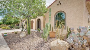 Un edificio con arcos, un jardín de cactus y un árbol.