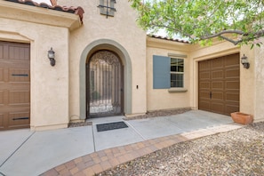 A building with a beige stucco exterior, a metal gate, and two brown garage doors. - Tranquil Home w/ Hot Tub in 55+ Florence Community (Florence)