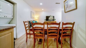 A dining area with a wooden table and chairs, a television, and a kitchen area with a stove. - Family-friendly Home 7 Mi to Dtwn San Bernardino! (Rialto)