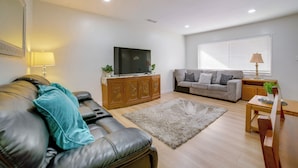 A living room with a leather sofa, a wooden cabinet, a television, a grey sofa, a wooden coffee table, and a window with blinds. - Family-friendly Home 7 Mi to Dtwn San Bernardino! (Rialto)