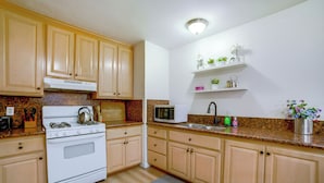 A kitchen with wooden cabinets, a stove, a microwave, and a sink. - Family-friendly Home 7 Mi to Dtwn San Bernardino! (Rialto)