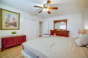 A bedroom with a bed, a ceiling fan, a dresser, a mirror, and a door. - Family-friendly Home 7 Mi to Dtwn San Bernardino! (Rialto)