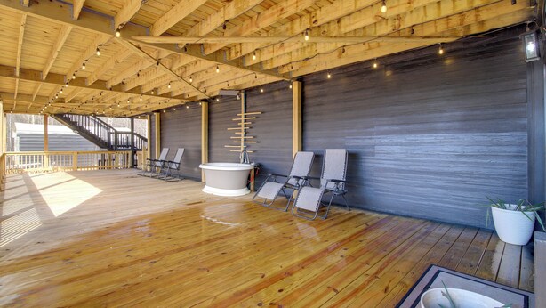 A wooden deck with a hot tub, lounge chairs, and a staircase leading to an upper level. - Huge 3-unit Commerce Estate Near ATL Dragway! (Commerce)