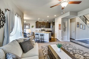 Una cocina moderna con una isla central, taburetes de bar y un comedor con mesa y sillas.
