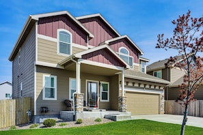 A two-story house with a front porch, a garage, and a small front yard.