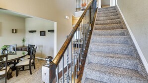 Un escalier avec une rampe en bois et des balustrades en métal, des marches recouvertes de moquette et un coin repas avec une table ronde et des chaises.