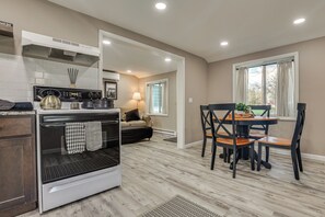 A modern kitchen with a stove, oven, and dining area with chairs and a table.