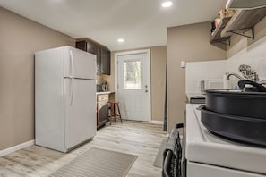 A compact kitchen with a refrigerator, stove, and wooden cabinets.