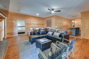 A log cabin interior with a sectional sofa, a dining table, and a ceiling fan. - Peaceful Retreat Near Callaway Gardens! (Shiloh)