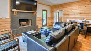 A log cabin interior with a fireplace, leather seating, and a dining area.