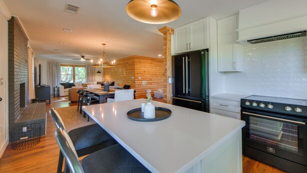 A modern kitchen with a central island, built-in appliances, and a dining area with a view.