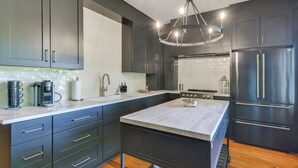 A modern kitchen with dark cabinetry, a central island, and a stainless steel refrigerator.
