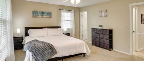 A bedroom with a bed, a ceiling fan, a dresser, and a door.