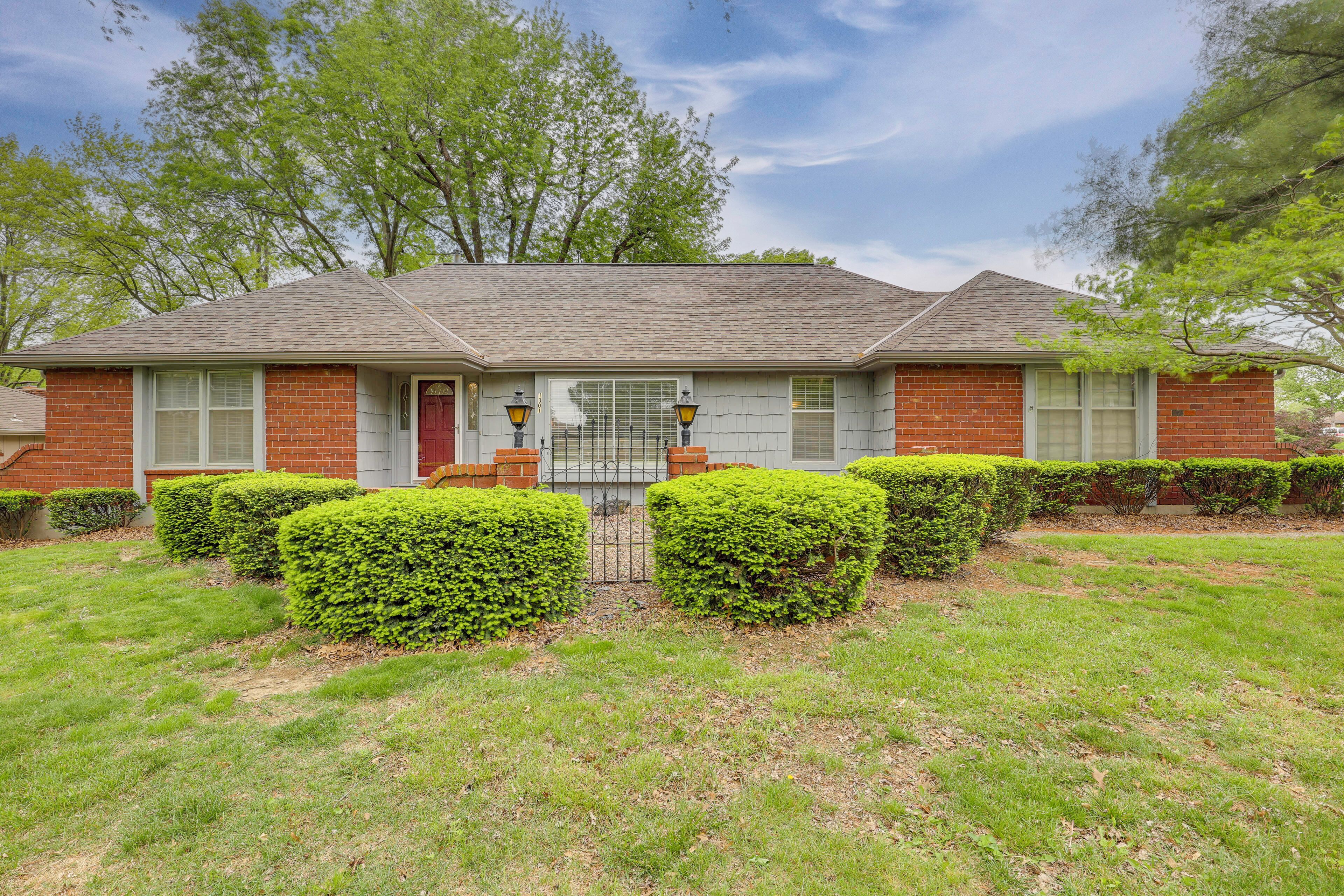 A two-story house with a brick facade, a front porch, and a well-maintained lawn.