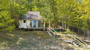 A house with a deck and stairs leading to a wooden platform.