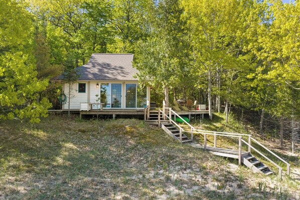 A house with a deck and stairs leading to a wooden platform.