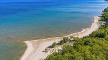 An aerial view of a beach with clear waters and a sandy shore.