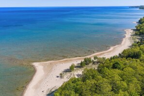 An aerial view of a beach with clear waters and a sandy shore.
