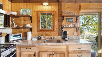 A wooden kitchen with a built-in oven, a sink, and a window.