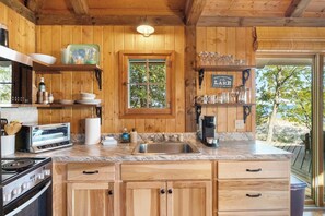 A wooden kitchen with a built-in oven, a sink, and a window.