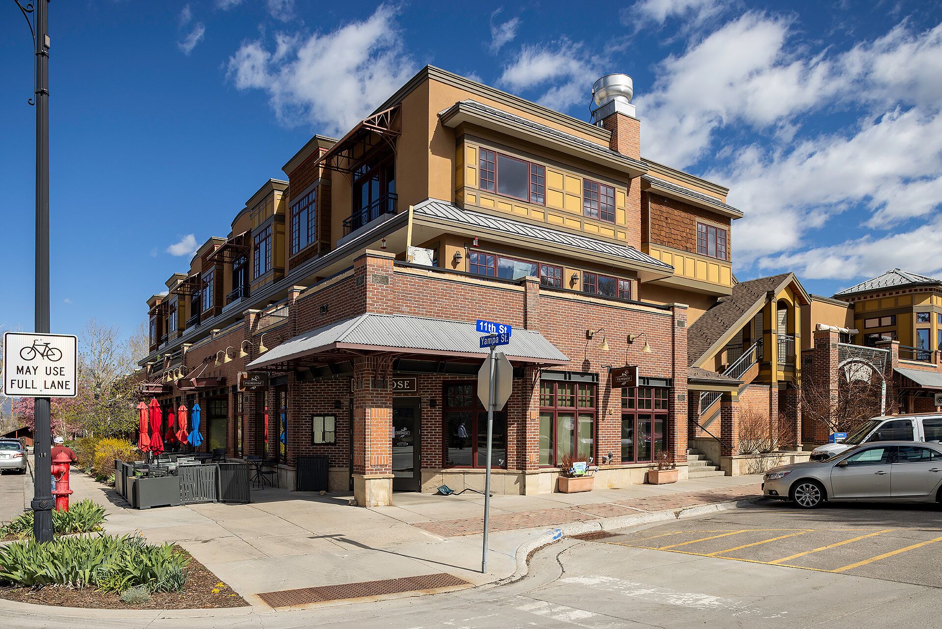 A multi-story building with a brick facade, a visible storefront, and a clear blue sky.