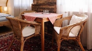 A room with a wooden wall, a dining table with chairs, a patterned rug, and a bed. - Gazdovsky dvor B&B Mini wellness (Bešeňová)