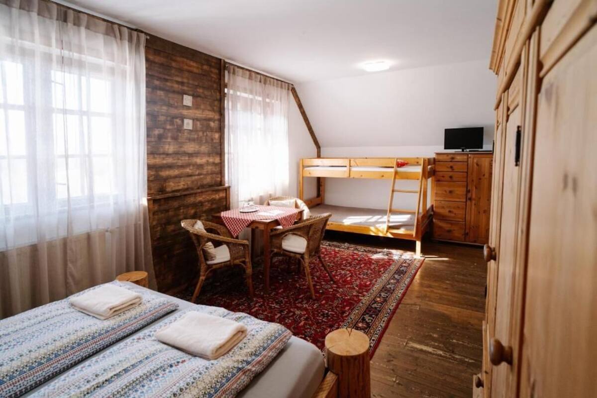 A room with a bunk bed, a desk with chairs, a television, and wooden cabinets.