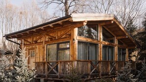 A wooden cabin with a balcony, large windows, and a snow-covered landscape. - Gazdovsky dvor B&B Mini wellness (Bešeňová)