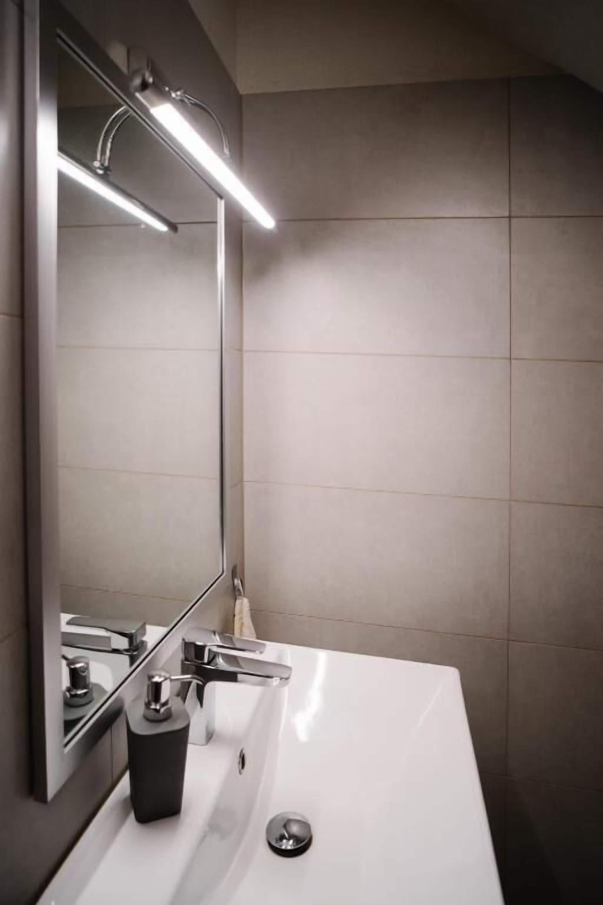 Un baño con un lavabo blanco, un espejo y un grifo moderno.