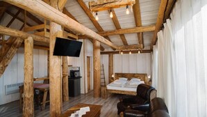 A rustic wooden room with a bed, a TV, a table, and a leather couch. - Gazdovsky dvor B&B Mini wellness (Bešeňová)