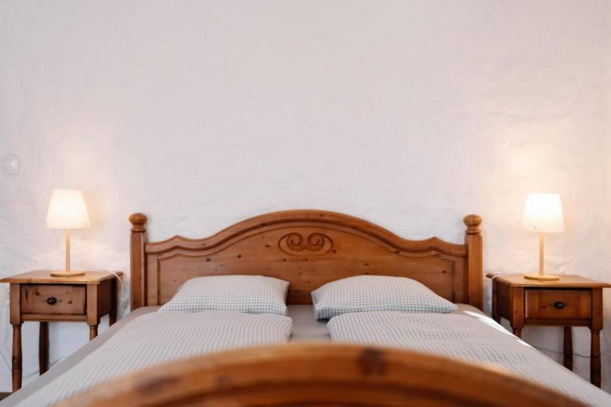 A double bed with a wooden headboard, two bedside tables with lamps, and a checkered bedspread.