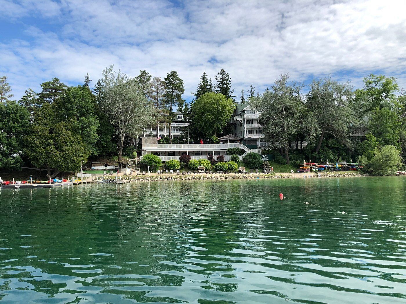 A lakeside hotel with a dock, boats, and a building with multiple stories and balconies.
