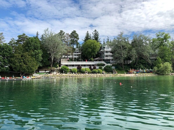 A lakeside hotel with a dock, boats, and a building with multiple stories and balconies.