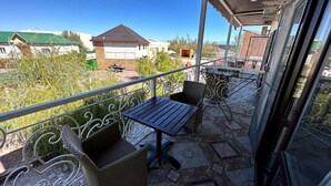 A balcony with a table and chairs, a view of the surrounding area, and a building in the background.