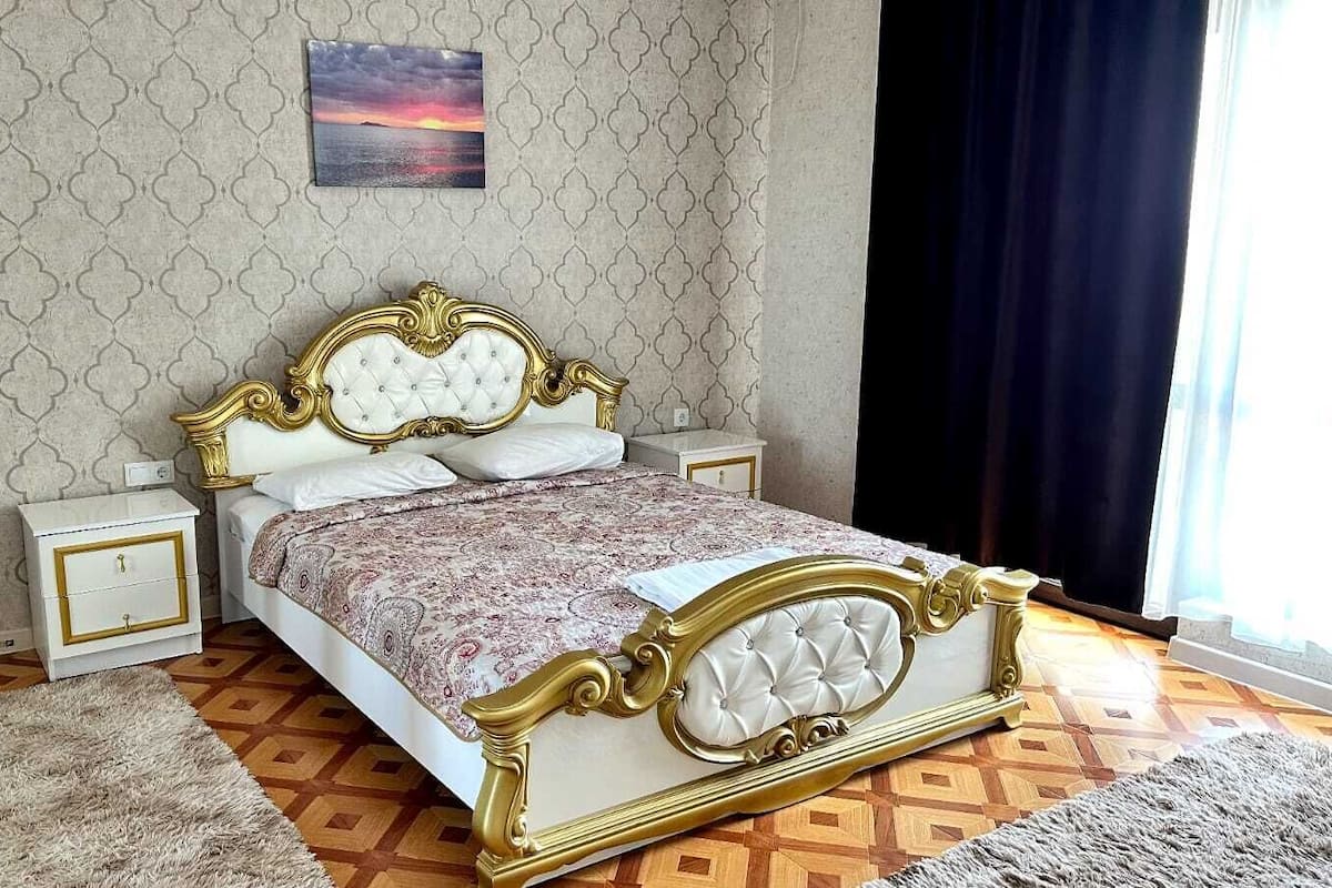 A bedroom with a bed, nightstands, a rug, and a wall-mounted picture.