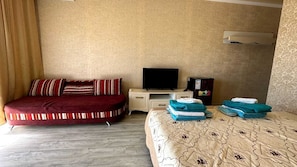 Una habitación de hotel con cama, televisión, escritorio y armario.