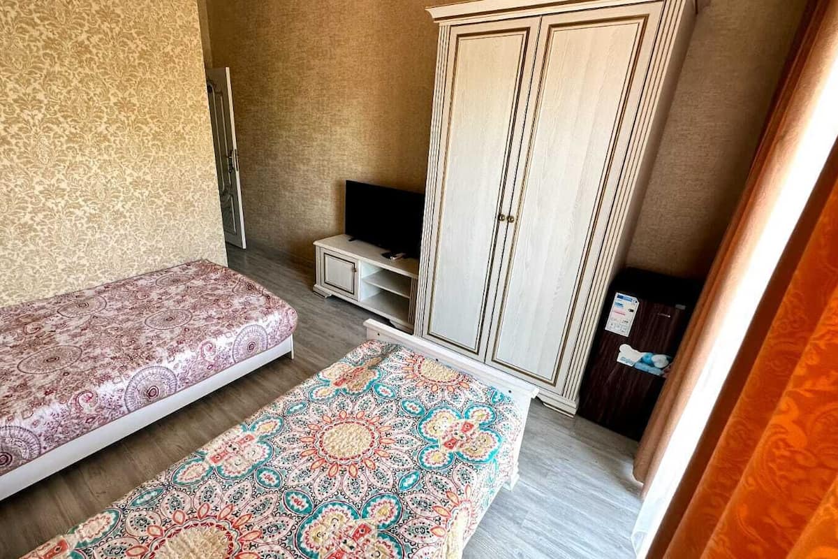 A room with a bed, a small table, a wardrobe, and a television.