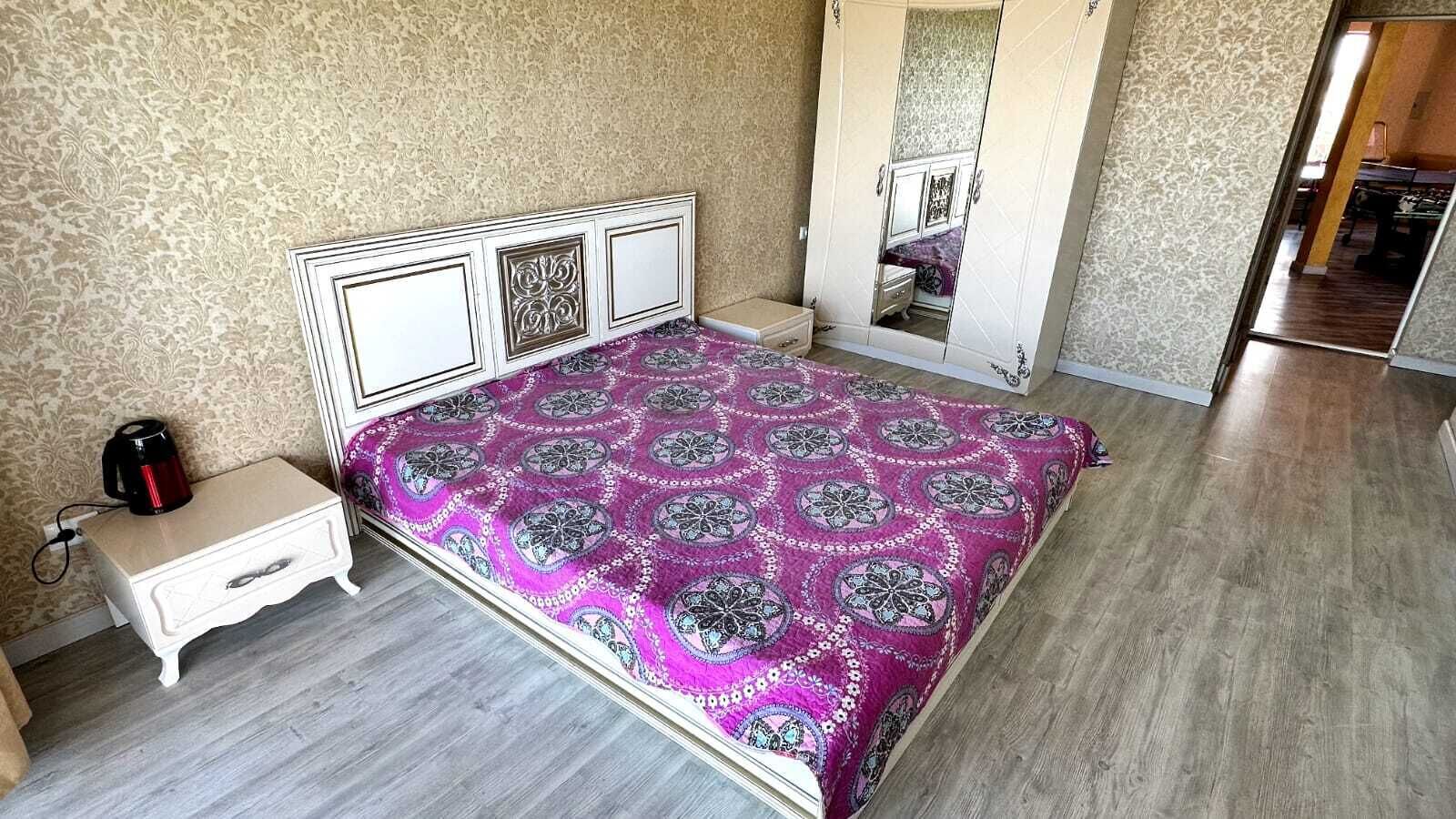 A bedroom with a bed, bedside table, and a mirror.