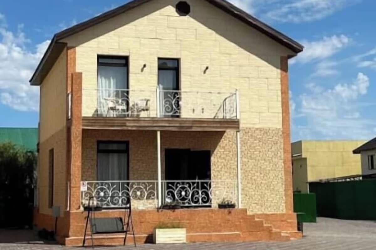 A two-story building with a balcony, a small porch, and a paved driveway.