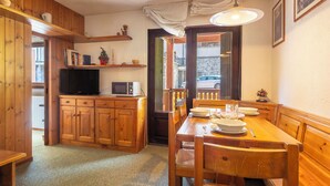 A wooden interior with a dining table, chairs, a television, and a microwave. - Cardinello Rosa by Interhome (Madesimo)