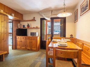 Ein Holzinterieur mit Esstisch, Stühlen, Fernseher und Mikrowelle.