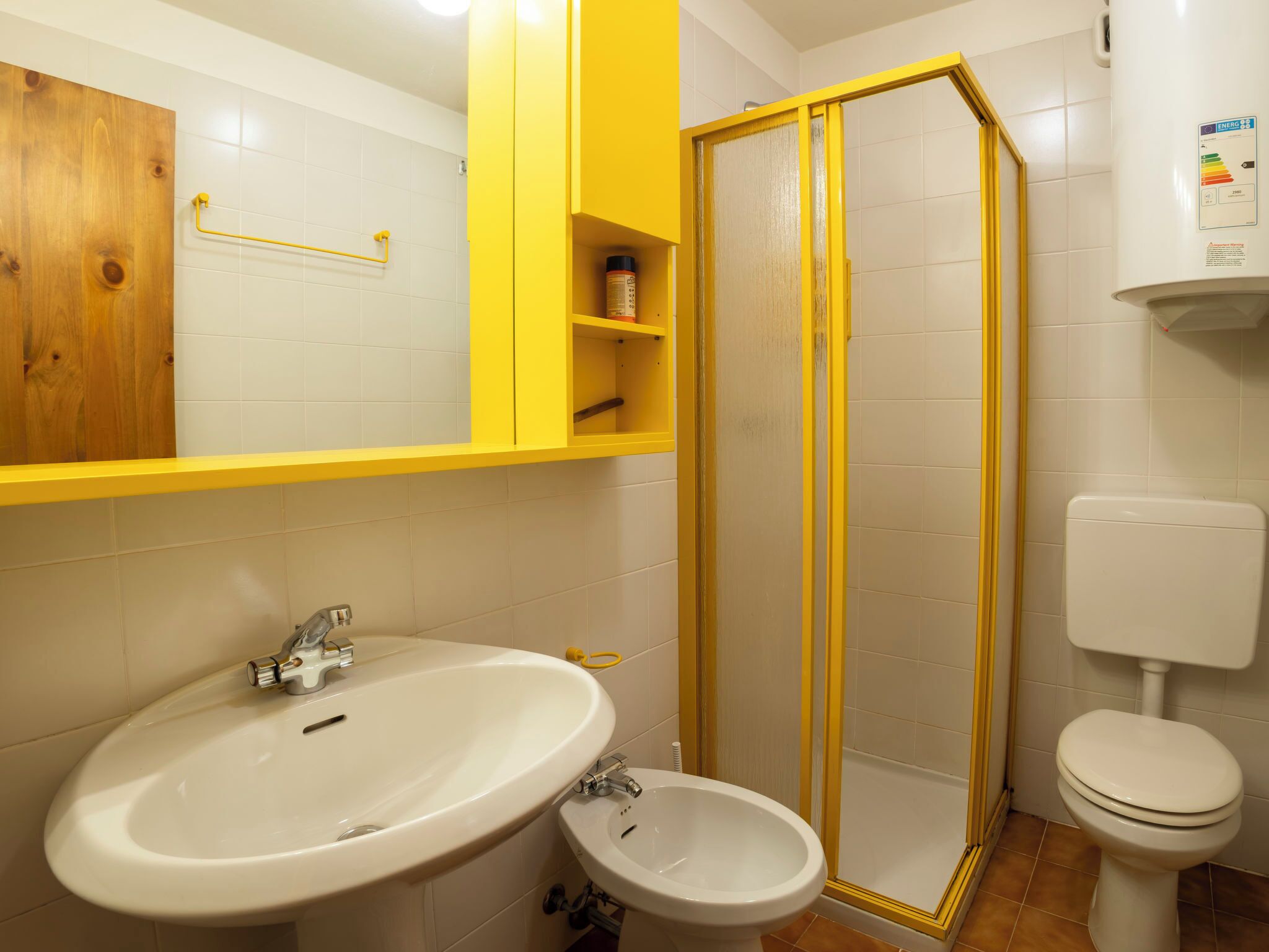Een badkamer met een wit wastafelmeubel, een douchecabine, toilet en een bidet.
